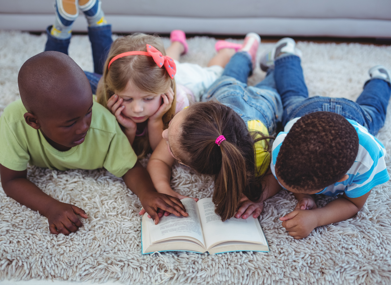 Photo of four children reading a book together
