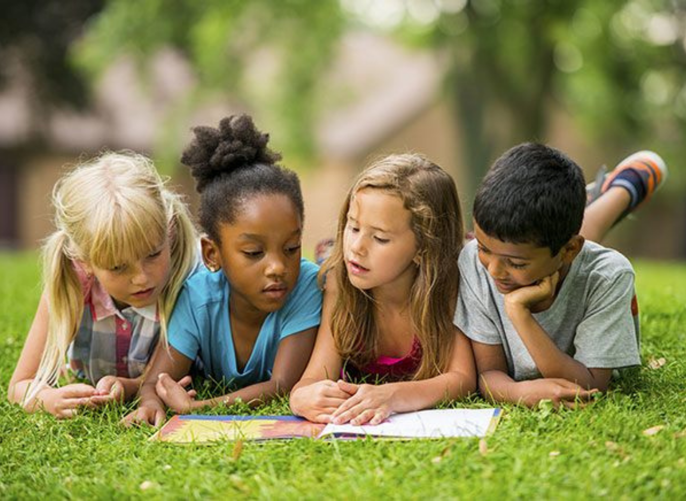 Photo of four kids reading a book together