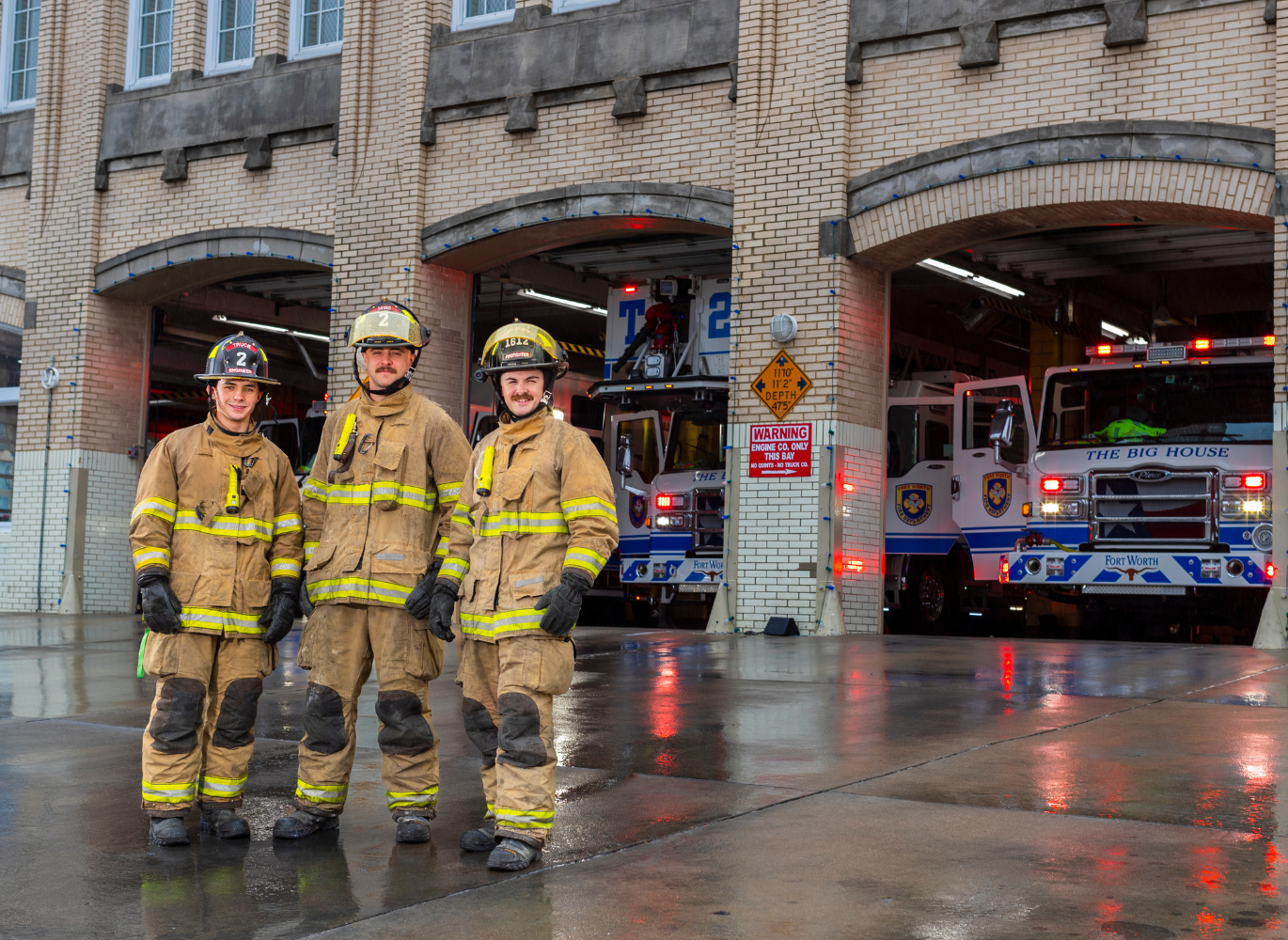 Photo of three firefighters standing outside of the fire station