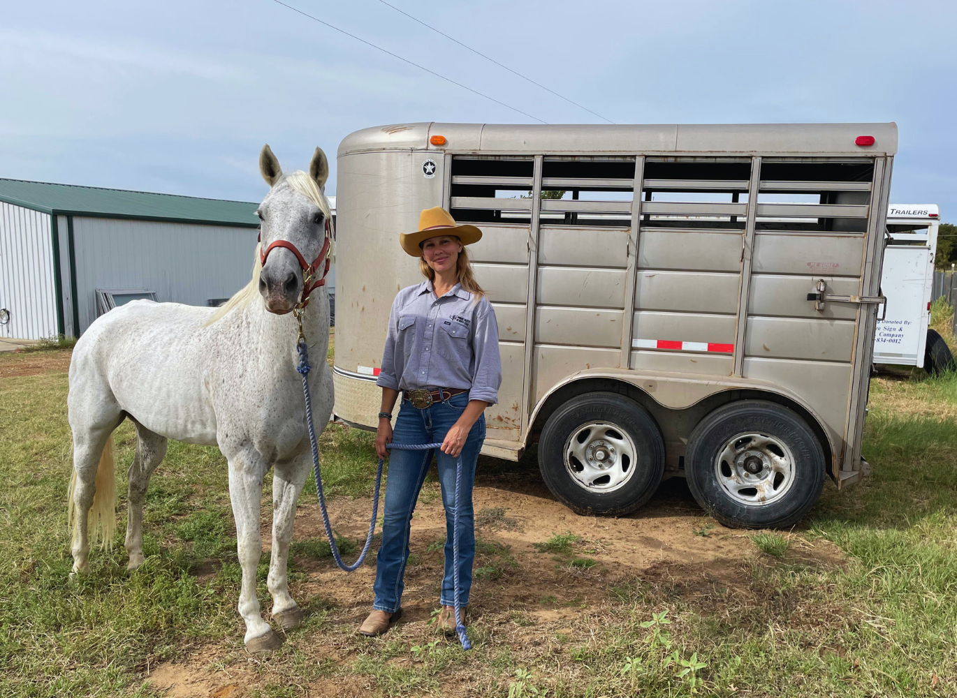 Photo of a women with a horse standing in front of a trailer